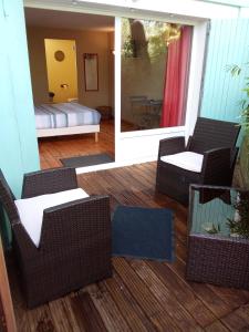 ヴィエル・サン・ジロンにあるLe mas des Landesの籐の椅子が備わるポーチ、ベッドが備わる部屋