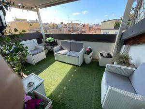 a patio with white chairs and grass on a balcony at Suite Indipendenza 58 in Bologna