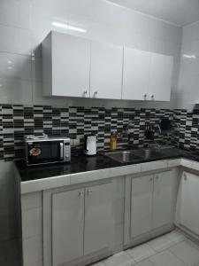 a kitchen with white cabinets and a sink and a microwave at Résidence Mami in Dakar