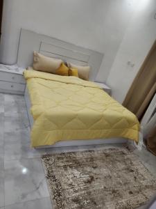 a bed with a yellow comforter in a room at Résidence Mami in Dakar