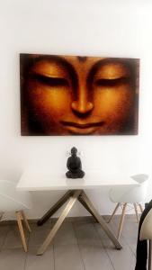 a man sitting on a table in front of a painting of a face at City Apartment in Vienna