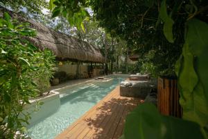 a swimming pool in a yard with a thatch roof at Zereno Boutique Hotel in Tulum