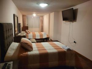 una camera d'albergo con due letti e una TV a schermo piatto di Amplio y lindo departamento. ad Arequipa