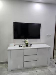 a white cabinet with a flat screen tv on a wall at Résidence Mami in Dakar
