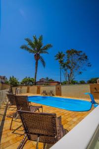 una piscina con sillas y una palmera en Ubatuba Eco Hotel, en Ubatuba