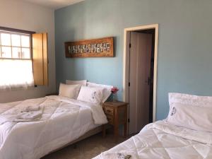 a bedroom with two beds with white sheets and a window at Pousada Vó Iris in Tiradentes