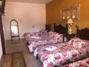 a hotel room with four beds and a mirror at Pousada Vó Iris in Tiradentes