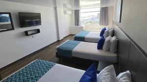 a hotel room with two beds and a tv at On Vacation Blue Tone in San Andrés