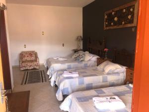 Zimmer mit 3 Betten und einem Stuhl in der Unterkunft Pousada Vó Iris in Tiradentes