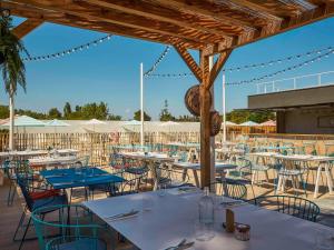 un ristorante con tavoli, sedie e ombrelloni di Ibis Styles Montpellier Aéroport Parc Des Expos a Mauguio
