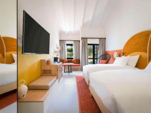 SO/ Sotogrande Spa & Golf Resort Hotel في سوتوغراندِ: غرفة فندقية بسريرين وتلفزيون بشاشة مسطحة