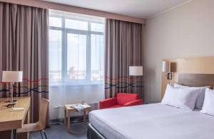 a hotel room with a bed and a red chair at Park Inn by Radisson Volgograd in Volgograd