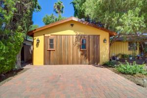 a yellow house with a garage with a brick driveway at Sleek Woodland Hills Retreat with Shared Pool and Yard in Woodland Hills