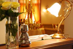 una mesa con una lámpara y un jarrón de flores. en Münsterländer Hof, en Cloppenburg