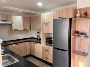 La cuisine est équipée d'armoires en bois et d'un réfrigérateur en acier inoxydable. dans l'établissement Luxueux appartement avec piscine à la Marina Saidia, à Saïdia
