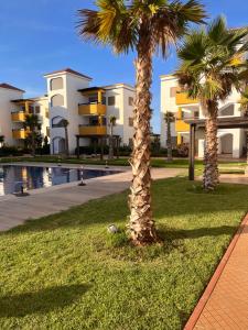 deux palmiers devant un bâtiment dans l'établissement Luxueux appartement avec piscine à la Marina Saidia, à Saïdia