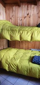 two beds in a wooden room with yellow sheets at Hike and Chill Homestay in Tinerhir