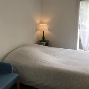 - une chambre avec un lit, une lampe et une chaise dans l'établissement Calme & zenitude aux portes de Strasbourg (Zénith), à Eckbolsheim