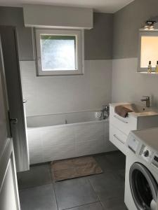 a bathroom with a tub and a sink and a washing machine at Calme & zenitude aux portes de Strasbourg (Zénith) in Eckbolsheim
