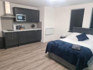 a bedroom with a large bed and a kitchen at Homestay by BIC Legends 1 in Batley Carr