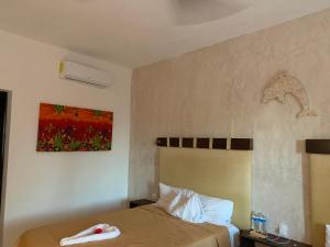 1 dormitorio con 1 cama y una pintura en la pared en CASA DELFINES RIO LAGARTOS, en Río Lagartos