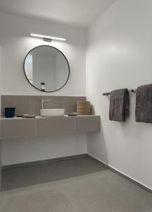 Baño blanco con lavabo y espejo en Hôtel Lune de Miel en Deshaies