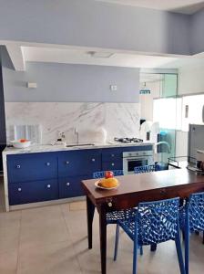 eine Küche mit einem Holztisch und blauen Schränken in der Unterkunft Apartamento charmoso no centro de Ubatuba in Ubatuba