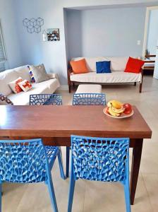 ein Holztisch mit Stühlen und ein Obstteller darauf in der Unterkunft Apartamento charmoso no centro de Ubatuba in Ubatuba