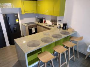 a kitchen with yellow and green cabinets and a counter with stools at Nuevo! Apartamento Oasis Central in Bogotá