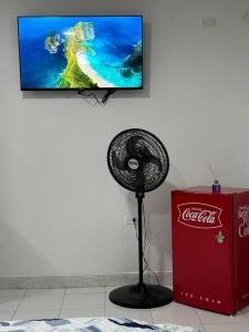 a fan in a room with a cocacola television at Habitacion independiente muy bien ubicado in Cartagena de Indias