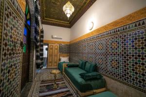 フェズにあるRiad Qamar Fezの緑のソファが備わるタイル張りの壁の客室です。