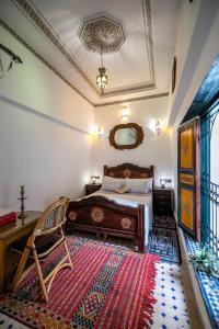 een slaapkamer met een bed, een stoel en een tapijt bij Riad Fes Allouch in Fès