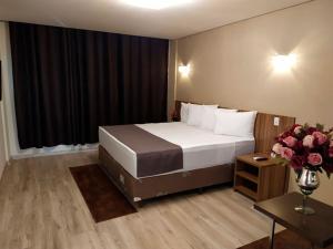 una habitación de hotel con una cama y una mesa con flores en Minas Platinum Hotel & Convention, en Conselheiro Lafaiete