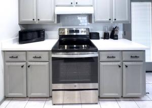 a kitchen with a stove and white cabinets at Chic, Quiet 2BR 2BA Near Shops & Restos! in McAllen +2 photos