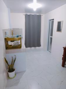 um quarto branco com um chuveiro e um vaso de plantas em Rendezvous Beach Resort - Cabongaoan em Tambobong