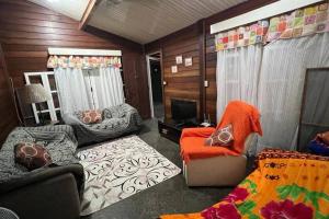 Una sala de estar con un sofá y sillas y un televisor. en Chalé Flamingo com Piscina Casa inteira em Morretes, en Morretes