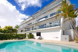 a villa with a swimming pool in front of a building at Commodore Apartment 5, Noosa Heads in Noosa Heads
