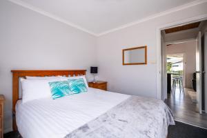 a bedroom with a large white bed with blue pillows at Mayson in Coles Bay