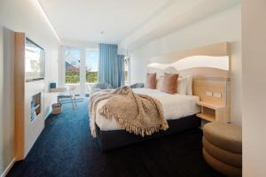 CitySide Hotel Tauranga في تاورانجا: غرفه فندقيه بسرير كبير وبلكونه