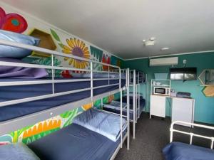 a room with three bunk beds and a kitchen at Hello! Accommodation in Tauranga