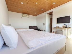 a bedroom with a white bed with a flat screen tv at Kumokuru 雲山初露 in Dongshi