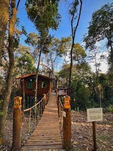 a wooden bridge leading to a cabin in the woods at Sequoia Casa na Árvore, Vila Mágica in Bueno Brandão