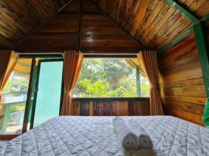 łóżko w pokoju z dużym oknem w obiekcie Ngọc Tiên Farmer Eco Lodge Cat Tiên w mieście Cat Tien