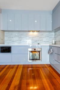 Il comprend une cuisine avec des placards blancs et du parquet. dans l'établissement Home Away From Home in Footscray, à Melbourne