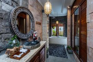 un bagno con un grande specchio e un lavandino di Barong Bali Resort Ubud ad Ubud