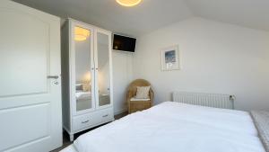 a white bedroom with a bed and a mirror at Kapitänshaus FeWo 3 in Cuxhaven