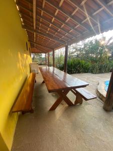 een houten picknicktafel en banken op een patio bij Chácara Tantan - Martins RN in Martins