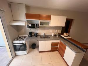 a small kitchen with white cabinets and a stove at Luis Maria Depto1 in San Martín