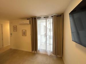 a living room with a large window and a flat screen tv at Apartamento céntrico con garage in Mercedes