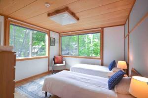 a room with two beds and two windows at Hakuba Colonsay- Amazing views 3bdr 2bth cottage in Hakuba